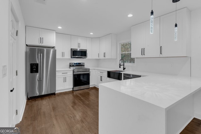 kitchen featuring white cabinets, stainless steel appliances, hanging light fixtures, and dark hardwood / wood-style floors