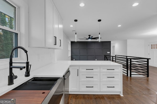 kitchen featuring kitchen peninsula, dark hardwood / wood-style flooring, sink, pendant lighting, and white cabinetry