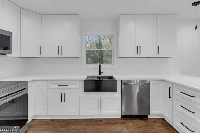 kitchen featuring stainless steel appliances, sink, white cabinets, and hanging light fixtures