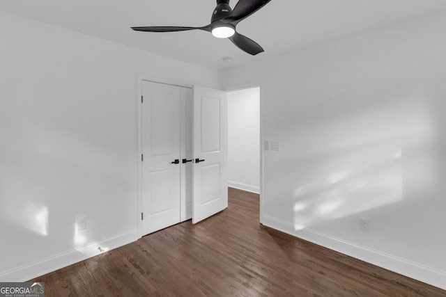 unfurnished bedroom with a closet, dark hardwood / wood-style floors, and ceiling fan