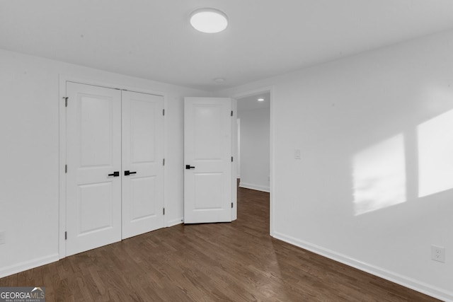 unfurnished bedroom featuring a closet and dark wood-type flooring