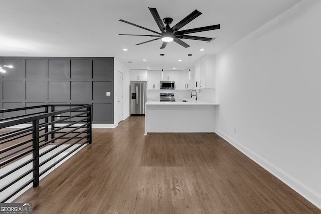 unfurnished living room featuring ceiling fan, sink, and dark wood-type flooring