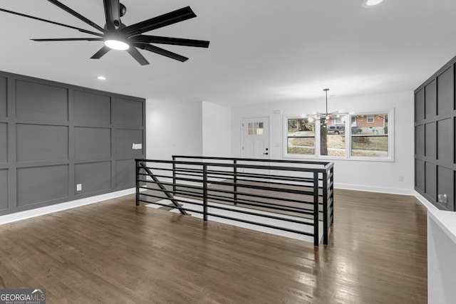 bedroom featuring ceiling fan with notable chandelier and dark wood-type flooring