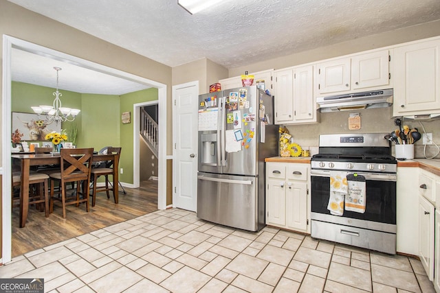 kitchen featuring appliances with stainless steel finishes, light hardwood / wood-style flooring, a chandelier, white cabinetry, and hanging light fixtures