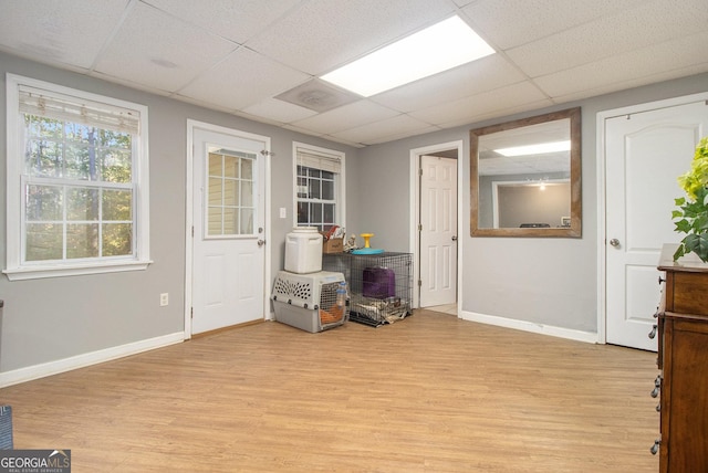 playroom featuring light wood-style floors, baseboards, and a paneled ceiling