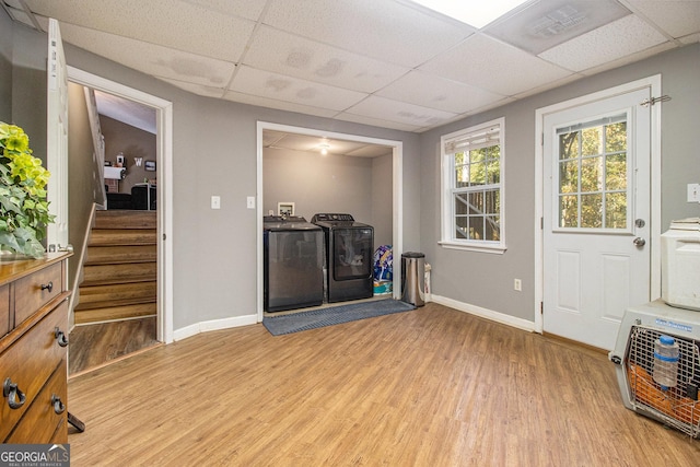 foyer featuring independent washer and dryer, light wood-style flooring, a drop ceiling, baseboards, and stairs