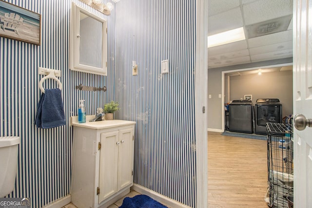 bathroom with washing machine and clothes dryer, wood-type flooring, toilet, a paneled ceiling, and vanity