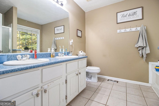 bathroom featuring toilet, vanity, tile patterned floors, and a bathing tub