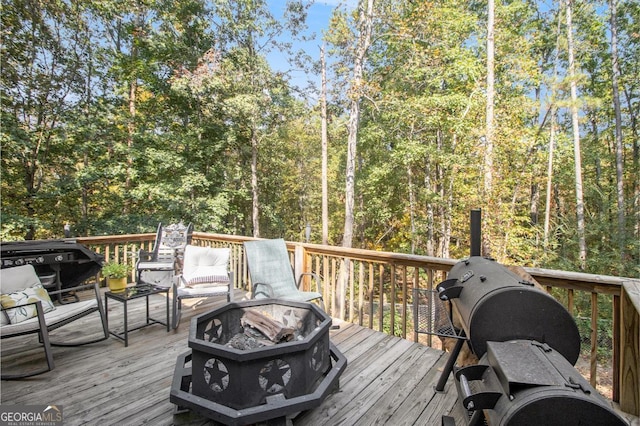 wooden terrace featuring a fire pit and a view of trees