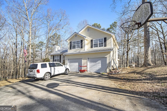 view of front of house featuring aphalt driveway, a garage, and a chimney