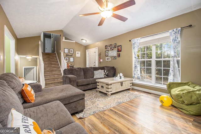 living room featuring ceiling fan, light wood-type flooring, and lofted ceiling