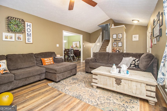 living room with stairs, vaulted ceiling, wood finished floors, and ceiling fan