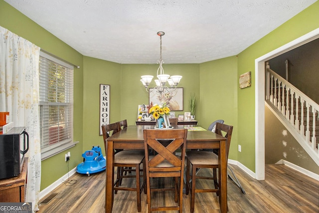 dining area featuring stairway, wood finished floors, baseboards, visible vents, and an inviting chandelier