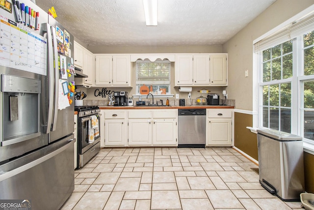 kitchen with sink, white cabinets, light tile patterned floors, and appliances with stainless steel finishes