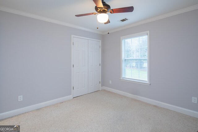 unfurnished bedroom with ceiling fan, ornamental molding, light carpet, and a closet