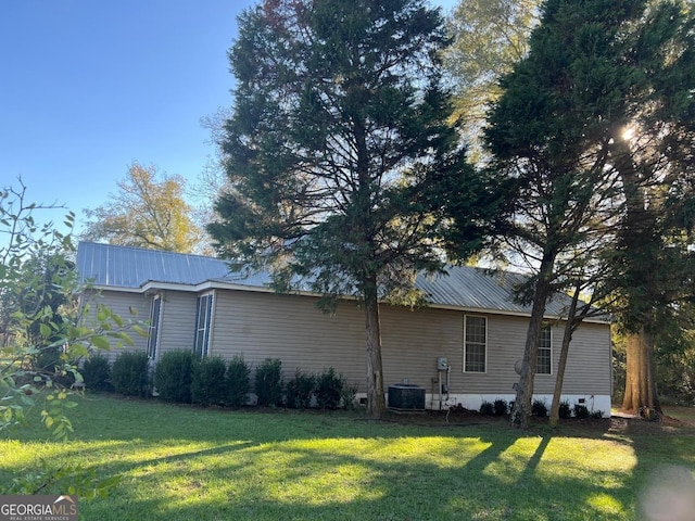 view of side of property with a lawn and central AC