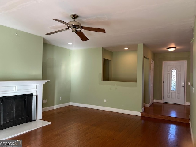 unfurnished living room featuring ceiling fan and dark wood-type flooring