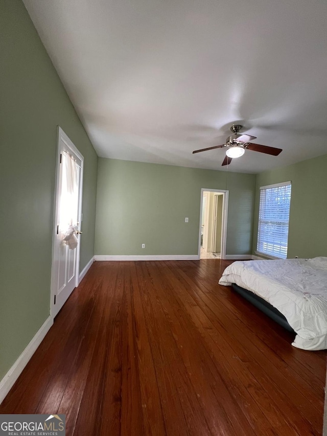 unfurnished bedroom with ceiling fan, dark hardwood / wood-style flooring, and multiple windows