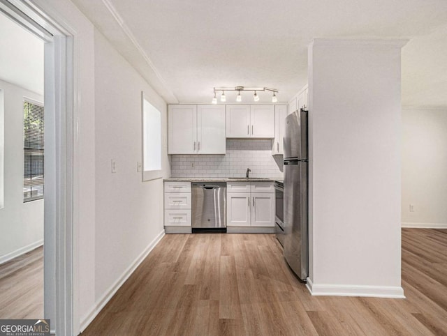 kitchen with sink, tasteful backsplash, appliances with stainless steel finishes, white cabinets, and light wood-type flooring