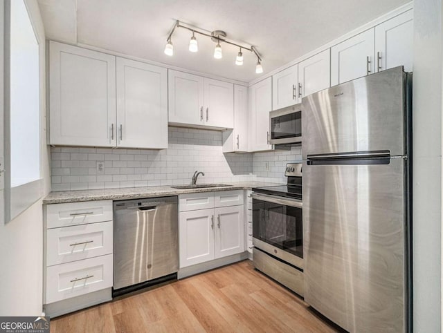 kitchen featuring white cabinetry, sink, light hardwood / wood-style flooring, backsplash, and appliances with stainless steel finishes