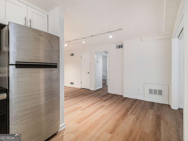 kitchen with white cabinets, stainless steel fridge, rail lighting, and light wood-type flooring