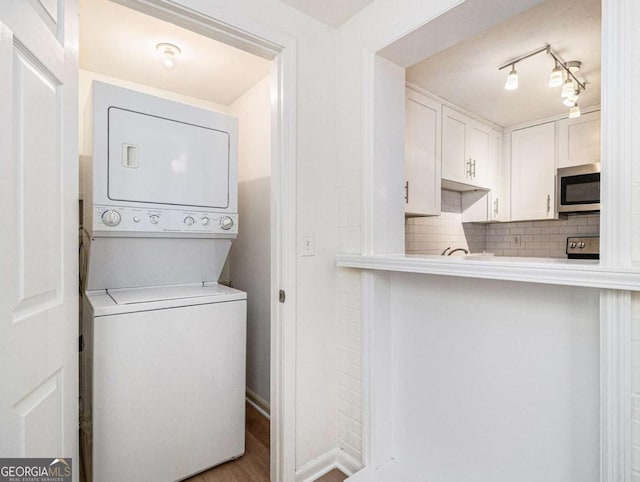 clothes washing area featuring hardwood / wood-style flooring and stacked washer / dryer