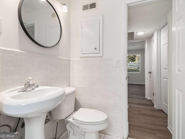 bathroom with toilet, tile walls, and hardwood / wood-style flooring