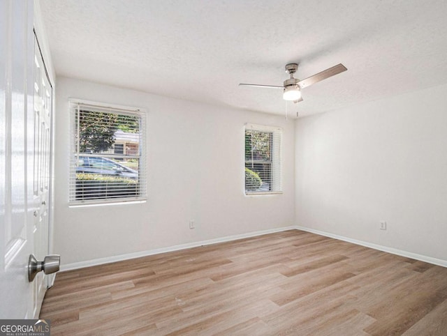 spare room featuring a textured ceiling, light wood-type flooring, a wealth of natural light, and ceiling fan