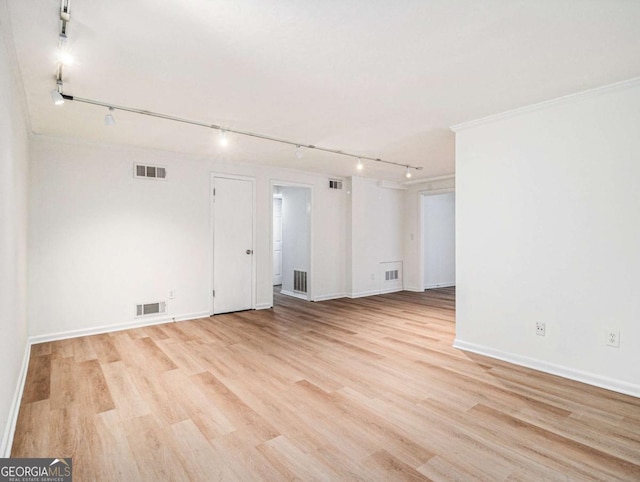 spare room featuring rail lighting, ornamental molding, and light wood-type flooring