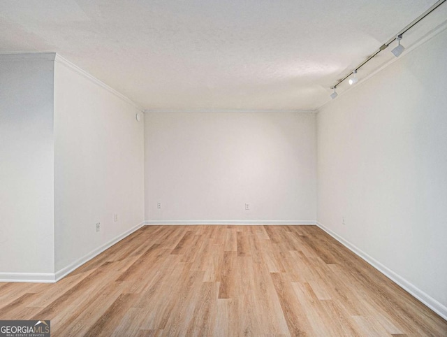 unfurnished room with ornamental molding, light wood-type flooring, a textured ceiling, and track lighting