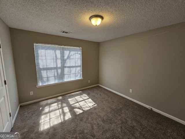 carpeted empty room with baseboards, visible vents, and a textured ceiling