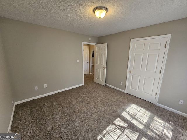 unfurnished bedroom featuring baseboards, carpet, and a textured ceiling