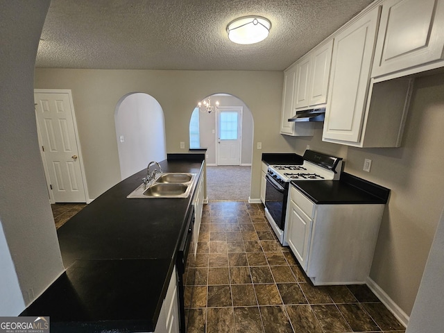 kitchen with gas stove, a sink, under cabinet range hood, white cabinetry, and dark countertops