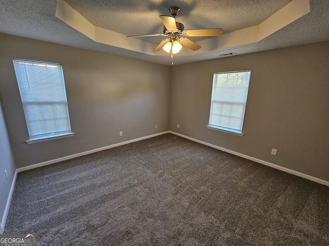 empty room featuring a tray ceiling, baseboards, a textured ceiling, and visible vents