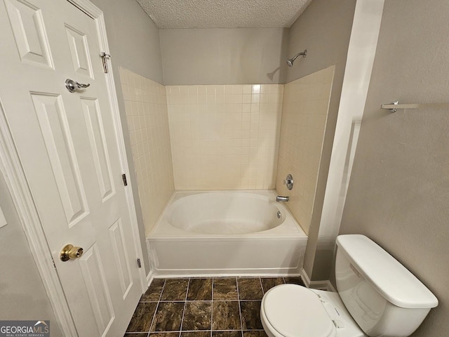 full bathroom featuring a textured ceiling, toilet, and bathing tub / shower combination