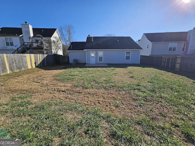 back of property with a lawn and a fenced backyard