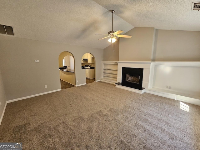 unfurnished living room with ceiling fan, dark carpet, a textured ceiling, and vaulted ceiling