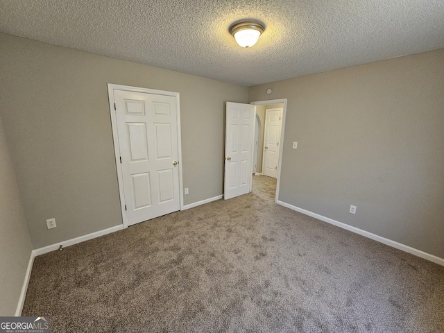 unfurnished bedroom featuring baseboards, carpet floors, and a textured ceiling