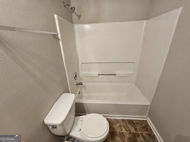 bathroom featuring toilet, a textured wall, and shower / bath combination