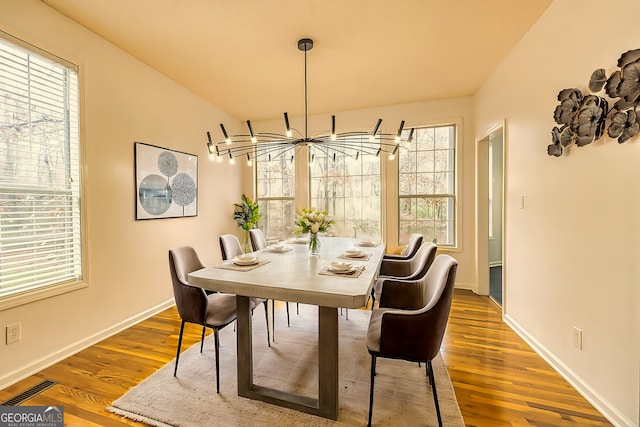 dining area with hardwood / wood-style floors, an inviting chandelier, and plenty of natural light