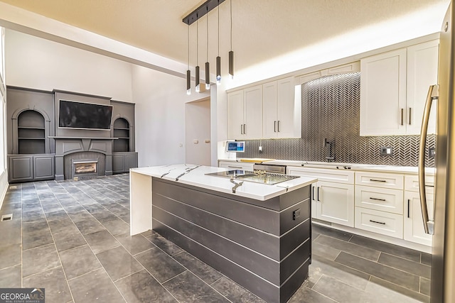 kitchen featuring a center island, backsplash, sink, light stone countertops, and decorative light fixtures