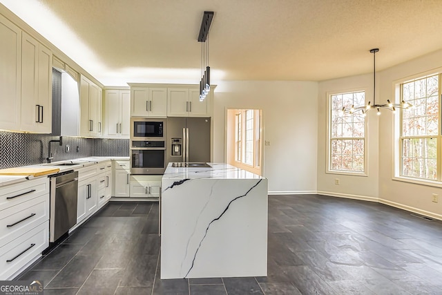 kitchen featuring an inviting chandelier, sink, decorative light fixtures, light stone counters, and stainless steel appliances