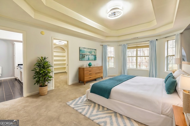 bedroom with carpet floors, a tray ceiling, and multiple windows