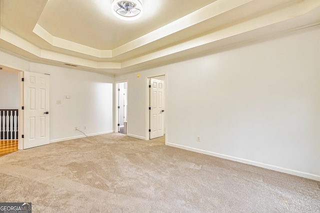 empty room with carpet flooring and a tray ceiling