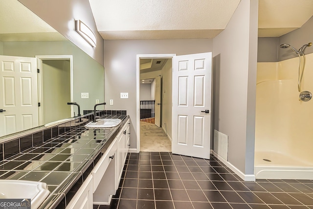 bathroom featuring tile patterned floors, vanity, a shower, and a textured ceiling