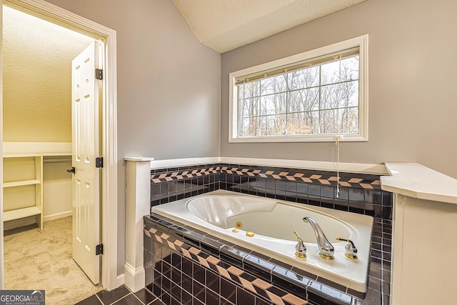 bathroom featuring a relaxing tiled tub and a textured ceiling