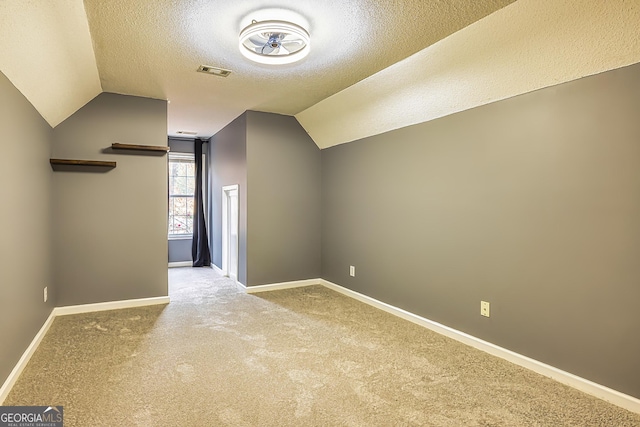 bonus room with carpet floors, a textured ceiling, and vaulted ceiling