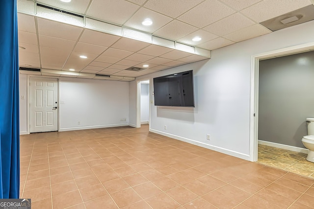 basement with a paneled ceiling and light tile patterned floors