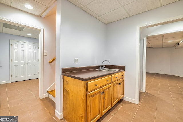 kitchen with a paneled ceiling, sink, and light tile patterned floors