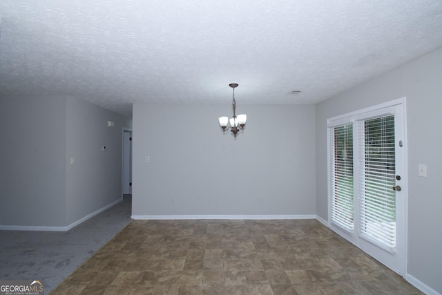 spare room with a textured ceiling and an inviting chandelier